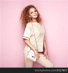 Fashion portrait of woman in summer outfit. Girl posing on pink background. Pink handbag. Stylish curly hairstyle. Glamour lady