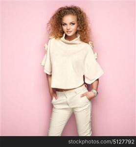Fashion portrait of woman in summer outfit. Girl posing on pink background. Stylish curly hairstyle. Glamour lady
