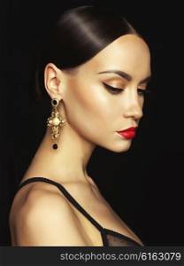 Fashion portrait of young beautiful lady with earring on black background
