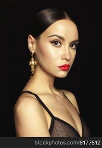 Fashion portrait of young beautiful lady with earring on black background