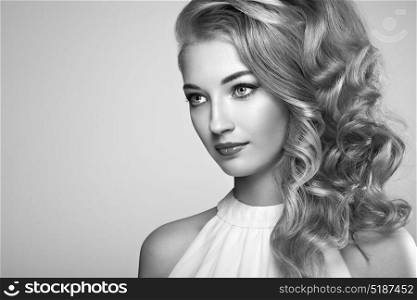Fashion portrait of young beautiful woman with elegant hairstyle. Blonde girl with long wavy hair. Perfect make-up. Black and white photo