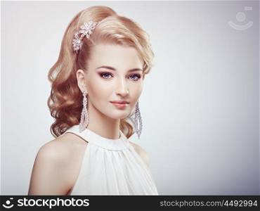 Fashion portrait of young beautiful woman with jewelry and elegant hairstyle. Blonde girl with long wavy hair. Perfect make-up. Beauty style woman with diamond accessories