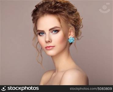 Fashion portrait of young beautiful woman with jewelry and elegant hairstyle. Beautiful model with curly hair. Perfect make-up. Beauty style model.