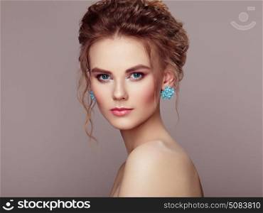 Fashion portrait of young beautiful woman with jewelry and elegant hairstyle. Beautiful model with curly hair. Perfect make-up. Beauty style model.