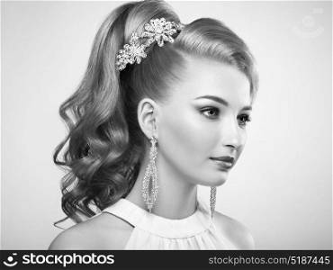 Fashion portrait of young beautiful woman with jewelry and elegant hairstyle. Blonde girl with long wavy hair. Perfect make-up. Black and white photo