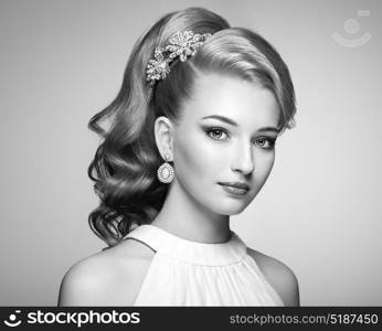 Fashion portrait of young beautiful woman with jewelry and elegant hairstyle. Blonde girl with long wavy hair. Perfect make-up. Black and white photo