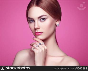 Fashion portrait of young beautiful woman with jewelry. Blonde girl. Perfect make-up and hairstyle. Beauty style woman with diamond accessories. Pink background