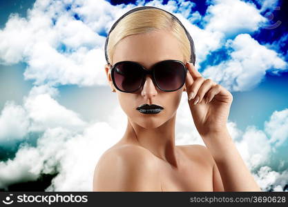 fashion portrait of young blond woman with hair style black lips and wearing sunglasses looking at the camera against white background