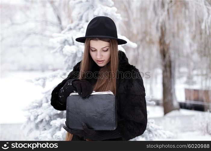 Fashion portrait of young hipster beautiful woman posing in black hat. Outdoors, lifestyle, winter.