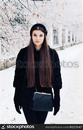 Fashion portrait of young hipster beautiful woman posing in black hat. Outdoors, lifestyle, winter.