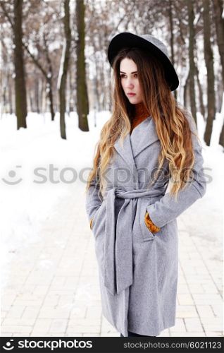 fashion portrait of young romantic dreaming hipster girl in grey coat and black hat.
