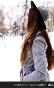 fashion portrait of young romantic dreaming hipster girl in grey coat and black hat.