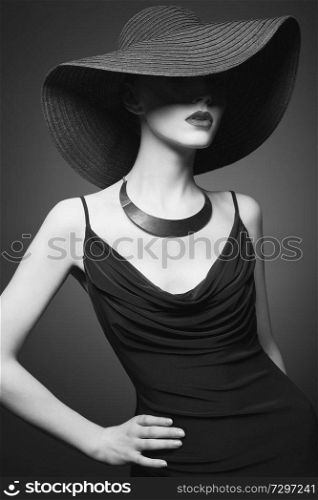 Fashion portrait of young sexy lady with beautiful black hat and evening dress. Stylish elegant woman with modern jewelry. Studio photo of pretty model on grey background.