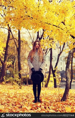Fashion portrait outdoors young long-haired beautiful model walking in the autumn park.