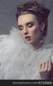 fashion portrait with romantic atmosphere of pretty girl with precious earrings, tiara in the elegant hair-style and retro dress with big white veil. closed eyes, theatrical expression