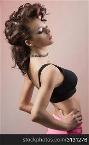 fashion sexy woman posing with creative curly hair-style and wearing black bra and pink trouser