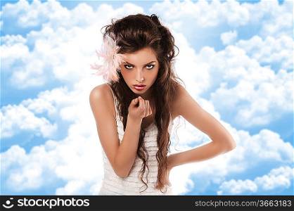 fashion shoot of a curly brunette wearing a white dress and a pink feather in her hair