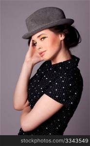 Fashion shoot of an attractive young woman wearing dark blouse and a hat.