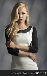 fashion shoot of blonde woman with elegant style, black and white dress, shiny accessory in the hair and pendant earring