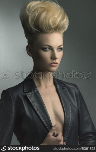fashion shoot of charming young girl posing with blonde creative modern hair-style and leather jacket
