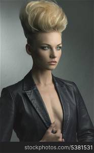fashion shoot of charming young girl posing with blonde creative modern hair-style and leather jacket