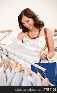 Fashion shopping - Happy young woman in shop choose clothes holding shopping bag