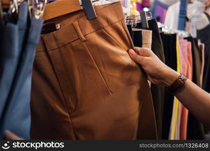 Fashion Shopping Lifestyle and Clothes for Women. Croped image of Female Customer Choosing Pant in Clothing Store