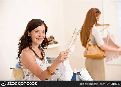 Fashion shopping - Two happy young woman choose clothes in shop