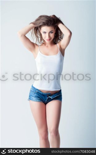 Fashion shot: a lovely young smiling girl in denim shorts and shirt. Model test