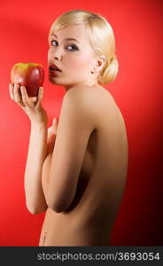 fashion shot of a glamour sensual girl with a red apple and nude body on red colored background