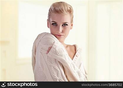 fashion shot of a gorgeous blonde girl with an elegant up-do wearing a warm winter sweater