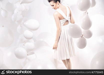 Fashion shot of a young woman among white balloons