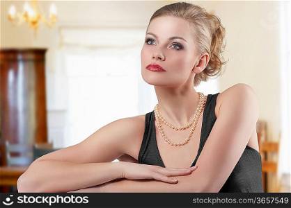 fashion shot of blond cute woman elegant dress and necklace jewellery posing over white