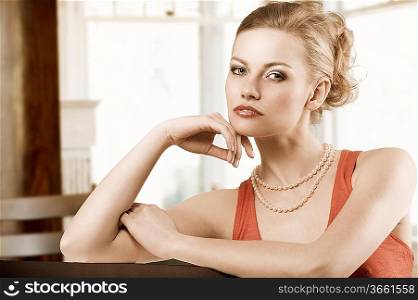 fashion shot of blond cute woman with elegant red dress and pearl necklace jewellery