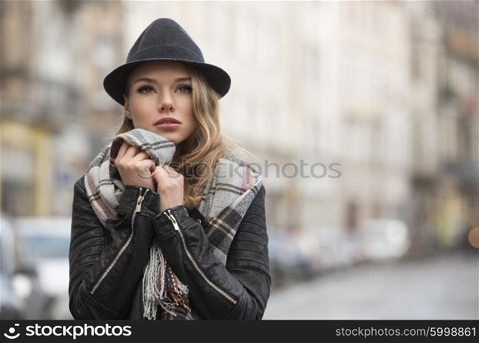 fashion shot portrait . outdoor in city contest , pretty young woman with freckles , wearing scarf and hat , in fall time