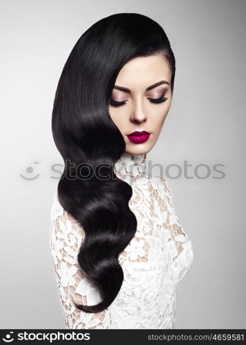 Fashion studio photo of beautiful model girl brunette with long curled hair and red lips. Hairstyle Hollywood wave. Wedding image hairstyle. Perfect makeup