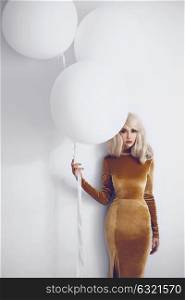 Fashion studio photo of beautiful slender woman with three white big balloons. Holidays and events. Stylish celebration