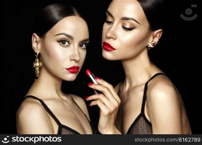 Fashion studio photo of two beautiful young ladys with red lipstick. Perfect face makeup. Beauty and jewelry