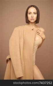 Fashion studio photo of young beautiful lady in beige coat on beige background. Total beige. Fashion look book. Warm Autumn. Warm Spring
