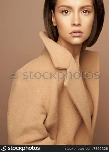 Fashion studio photo of young beautiful lady in beige coat on beige background. Total beige. Fashion look book. Warm Autumn. Warm Spring
