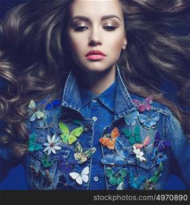 Fashion studio photo of young beauty woman with a lot of brooches on her jeans jacket. Denim clothes. Jeans trend. Magnificent hair