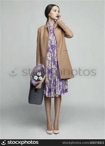 Fashion studio photo of young stylish woman. Beige coat, bouquet of lavender. Catalogue clothes. Lookbook