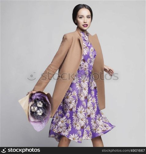 Fashion studio photo of young stylish woman. Beige coat, lilac dress, bouquet of lavender. Catalogue clothes. Lookbook