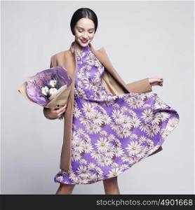 Fashion studio photo of young stylish woman. Beige coat, lilac dress, bouquet of lavender. Catalogue clothes and accessories. Lookbook