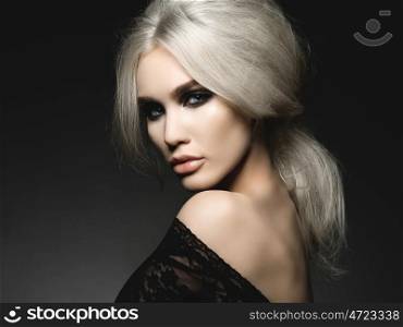 Fashion studio portrait of beautiful blonde woman with elegant hairstyle on black background