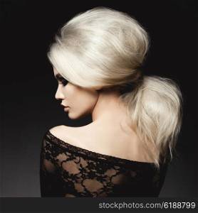 Fashion studio portrait of beautiful blonde woman with elegant hairstyle on black background