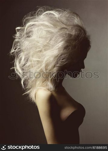 Fashion studio portrait of beautiful blonde woman with volume hairstyle on black background