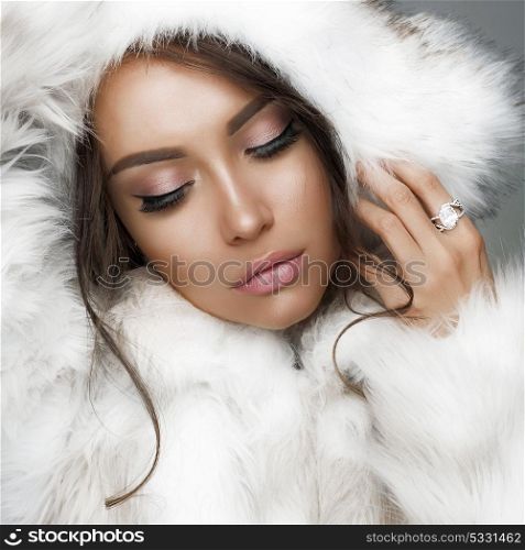 Fashion studio portrait of beautiful lady in white fur coat and fur hat. Winter beauty in luxury. Fashion fur. Beautiful woman in luxury fur coat. Fashion model posing in eco-fur coat and eco-fur hat