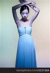 Fashion studio portrait of beautiful woman in azure dress on colorful background. Asian beauty.