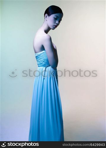 Fashion studio portrait of beautiful woman in azure dress on colorful background. Asian beauty.
